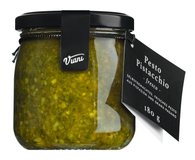 Frisches Pistazienpesto in einem Glas, garniert mit ganzen Pistazien und frischem Basilikum