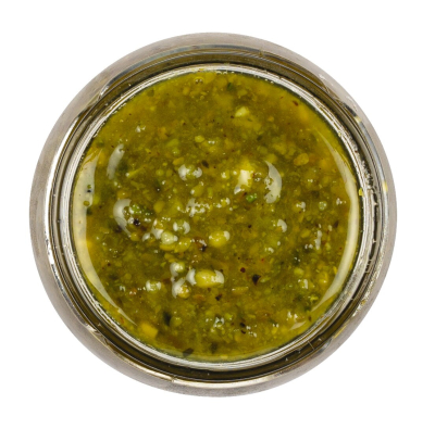 Frisches Pistazienpesto in einem Glas, garniert mit ganzen Pistazien und frischem Basilikum