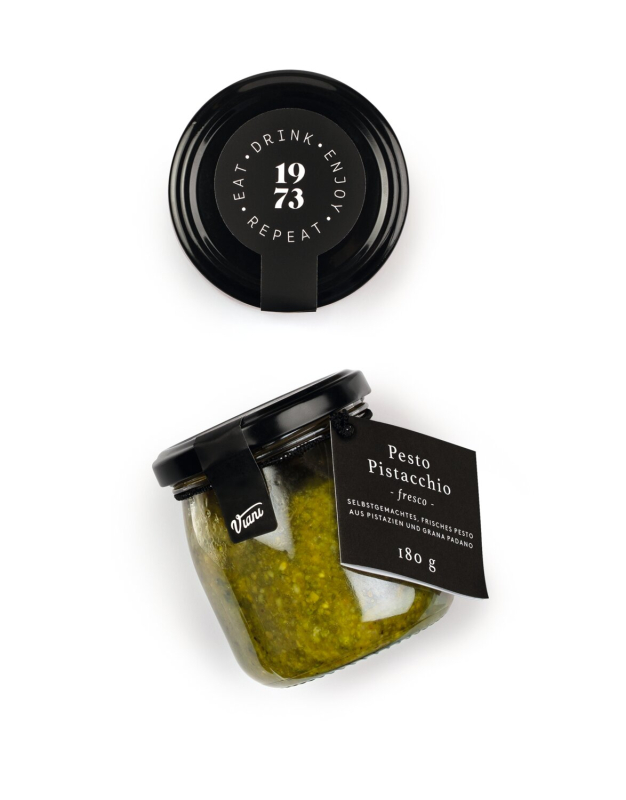 Frisches Pistazienpesto in einem Glas, garniert mit ganzen Pistazien und frischem Basilikum