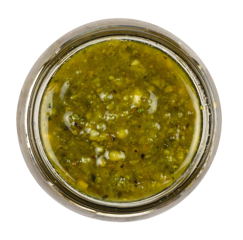 Frisches Pistazienpesto in einem Glas, garniert mit ganzen Pistazien und frischem Basilikum
